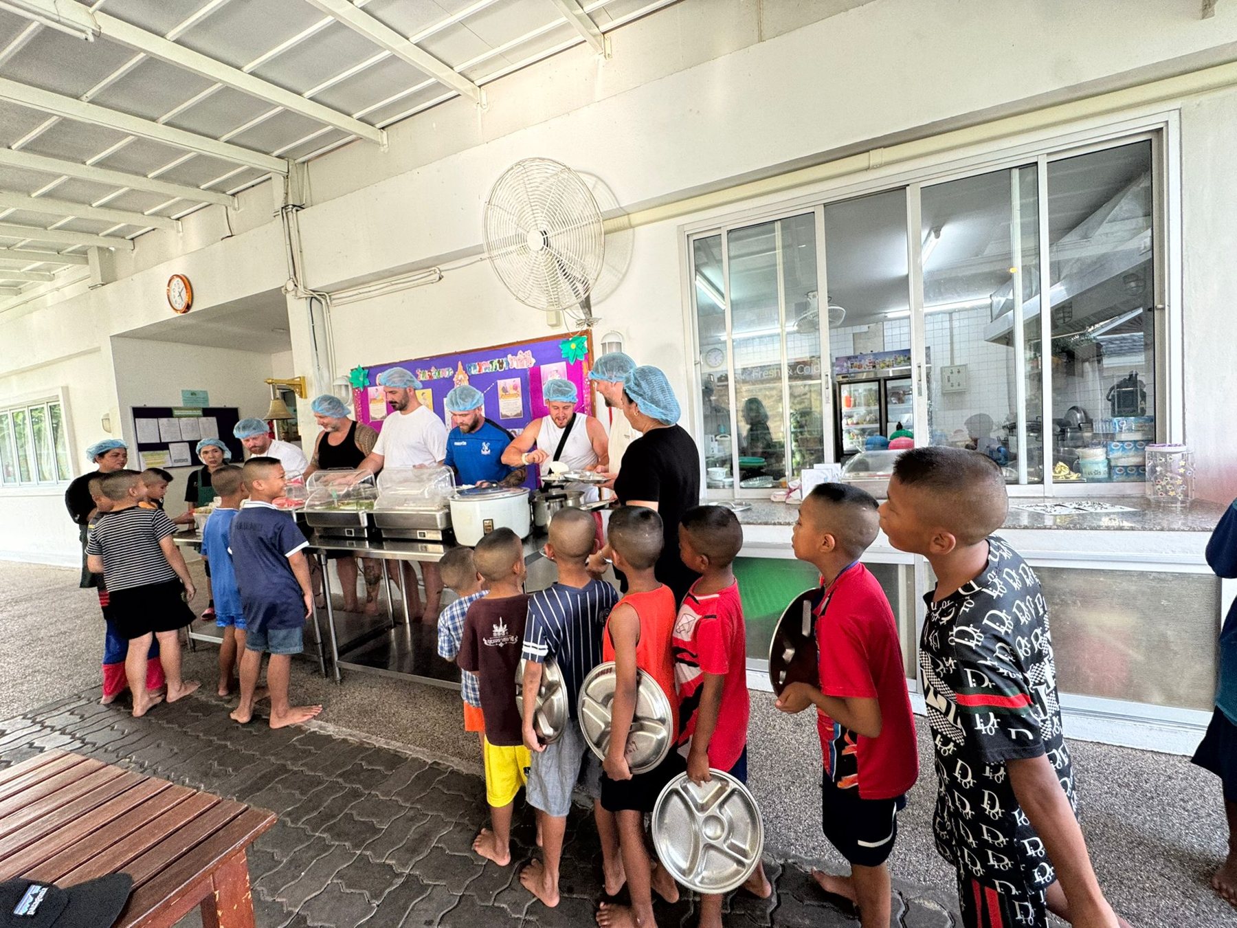 Veterans serving food to local children at a community kitchen outreach event in Thailand